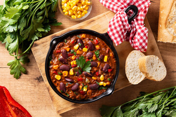 Traditional mexican tex mex chili con carne in iron pan on wooden table