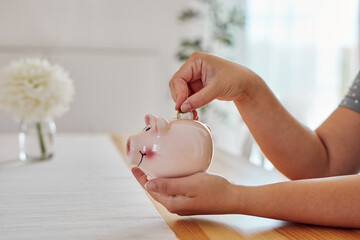 A woman puts a one euro coin into a piggy bank