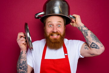 Happy chef with beard and red apron plays with pot