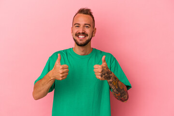 Young caucasian man with tattoos isolated on pink background  smiling and raising thumb up