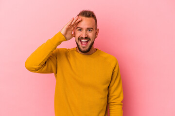 Young caucasian man with tattoos isolated on pink background  shouts loud, keeps eyes opened and hands tense.