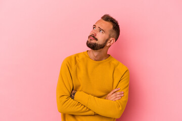 Young caucasian man with tattoos isolated on pink background  dreaming of achieving goals and...