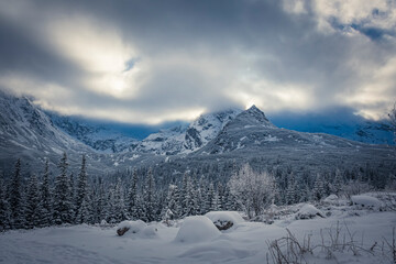 Majestic Hala Gąsienicowa view in winter, High Tatra Mountains, Poland. Dramatic cloudscape over the peaks. Selective focus on the ridge, blurred background.