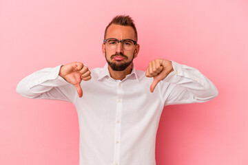 Young caucasian man with tattoos isolated on pink background  showing a dislike gesture, thumbs down. Disagreement concept.