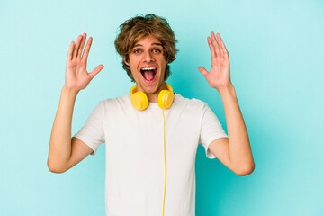 Young caucasian man listening to music isolated on blue background  receiving a pleasant surprise,...