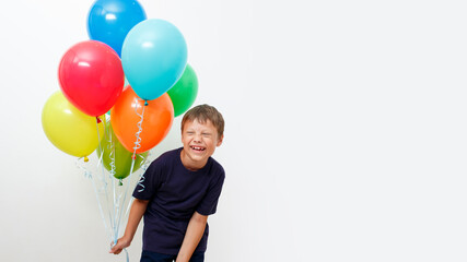 Happy eight year old boy with an armful of bright colorfull balloons celebrates birthday.