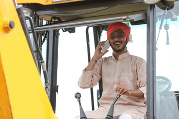 Fototapeta na wymiar Indian man talking on smartphone and working on heavy earth moving machinery
