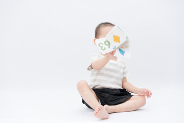 A little asian boy takes a portrait in a white background shed