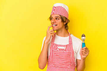 Young ice cream maker man with makeup holding spoon isolated on yellow background  relaxed thinking about something looking at a copy space.