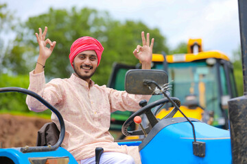 Technology and people concept, Portrait of young indian farmer with tractor