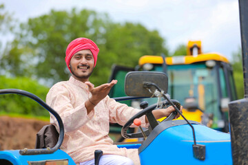 Technology and people concept, Portrait of young indian farmer with tractor