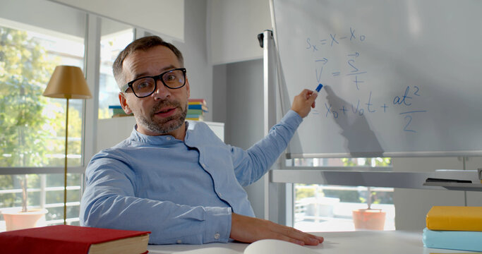 Mature teacher having online class through video call and explaining maths.