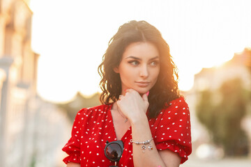 Elegant beautiful italian girl in a fashionable red dress with a stylish silver bracelet on her arm...