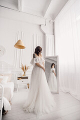 The bride in a wedding dress near the mirror