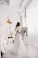 Fototapeta premium The bride in a wedding dress near the mirror