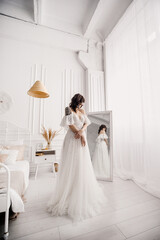 The bride in a wedding dress near the mirror