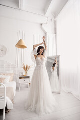 Naklejka premium The bride in a wedding dress near the mirror
