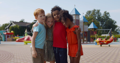 Group of multiethnic kindergarten kids friends hug at playground