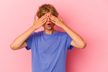 Young caucasian man with make up isolated on pink background afraid covering eyes with hands.