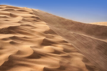 Lonely sand dunes in a strong wind under the sky against the background of arid desert