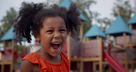 Medium shot of cute afro-american little girl yelling on playground