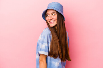 Naklejka premium Young caucasian woman isolated on pink background looks aside smiling, cheerful and pleasant.