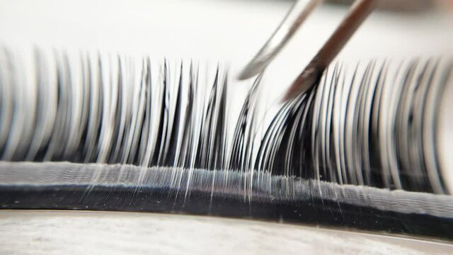 Hairing fake lashes for eyelash extensions with tweezers 