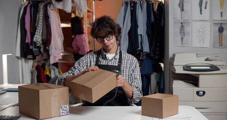 Male online clothes store worker scanning parcel bar code packing order