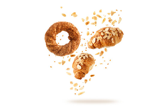 Fresh baked turkish simit sesame bagel, french butter almond nut croissants flying with seeds and crumbs isolated on white