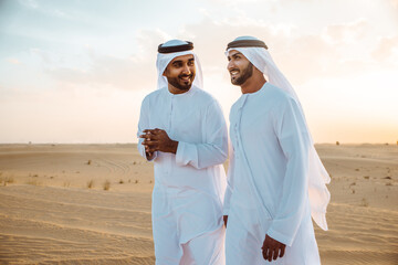 Two business men wearing traditional uae white kandura spending time in the desert of Dubai