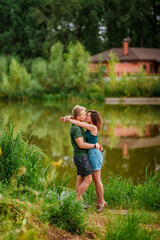 A beautiful couple in love, a man and a woman, embrace on the shore of a summer lake. Amazing natural landscape