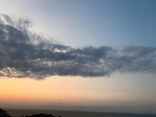 Blue and orange sunset sky with sun rays, dark clouds.