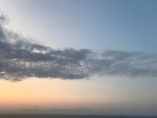 Blue and orange sunset sky with sun rays, dark clouds.