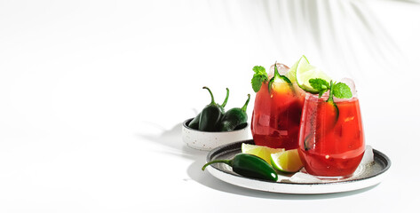 Spicy cocktail with vodka, tomato juice, jalapeno pepper, ice, lime and salt, white background, hard light, negative space