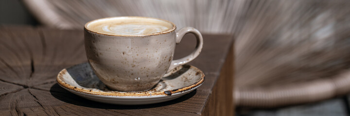 Cup of black coffee with milk in beige craft cup on a solid wood oak coffee table