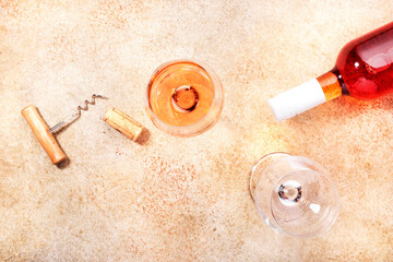 Rose wine glass with bottle on the beige table. Copy Space, top view