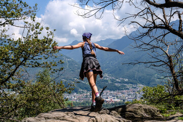 Mädchen steht auf einem Felsen und stellt sich mit ausgebreiteten Armen in den Wind