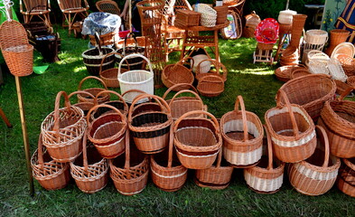 Fototapeta premium A small collection of wicker backets made by hand and used to carry various items seen on a pavement next to a massive shrub during a medieval fair on a Polish countryside