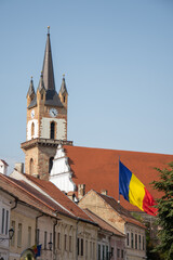 Fototapeta premium Evangelical Church Tower in Bistrita ,august 2021,and the flag of Romania ,view from Nicolae Titulescu street