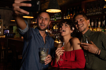 Happy friends taking selfie in bar