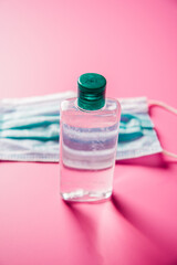 Coronavirus prevention medical surgical masks and hand sanitizer gel for hand hygiene. Corona virus protection on pink background.
