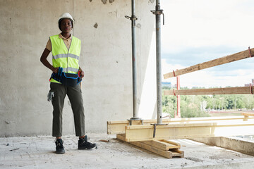 Full length portrait of young African-American woman working at construction site and smiling at camera, copy space