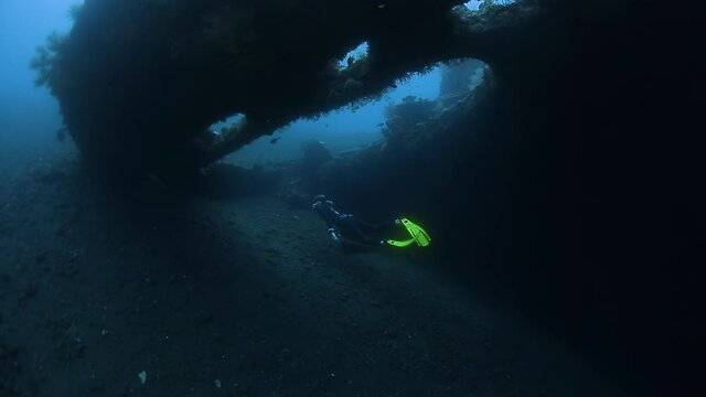 Freediver at USAT Liberty wreck in Bali. Woman freediver swims underwater near the shipwreck and explores the area