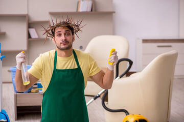 Young male contractor wearing prickly wreath on head cleaning th