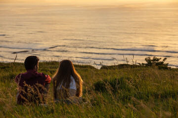 sweet young couple enjoying sunset together in front of the sea