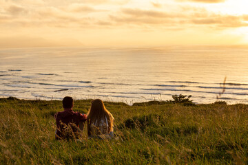 sweet young couple enjoying sunset together in front of the sea
