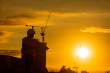 Fototapeta na wymiar silhouette of engineer and construction site background at sunset