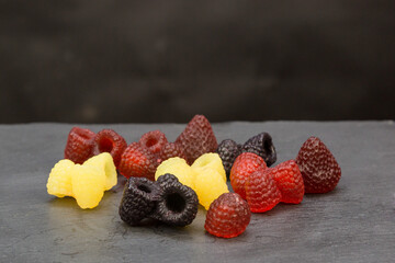 Bright scattered handmade soap in form of raspberries and blackberries, strawberries on a gray background.