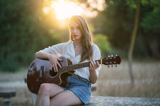 Chica joven en parque natural con guitarra acustica
