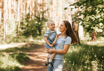 A young mother plays with her young son in the park in the summer